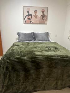 Una cama con una manta verde encima. en Excelente Apto setor Bueno 1101, en Goiânia