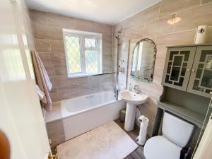 a bathroom with a tub and a sink and a toilet at Stunning Modern Cozy 5 star 3 bedroom house-Free Parking Greater London Metro Stations hosted by Tony in Catford