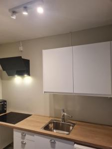 uma cozinha com um lavatório e armários brancos em Privat room in shared 3 rooms apartment Manglerud em Oslo