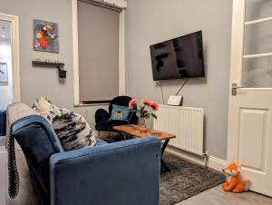 ein Wohnzimmer mit einem blauen Sofa und einem TV in der Unterkunft Entire Apartment Near Newcastle City Centre, West Jesmond. in Town Moor
