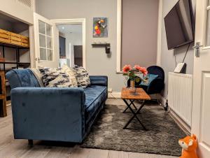 ein blaues Sofa im Wohnzimmer mit einem Tisch in der Unterkunft Entire Apartment Near Newcastle City Centre, West Jesmond. in Town Moor