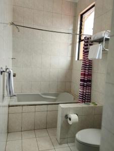 y baño con bañera, aseo y lavamanos. en Hotel Valladolid en Heredia