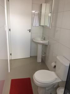 a white bathroom with a toilet and a sink at Hotel Mascarello in Planalto +7 photos