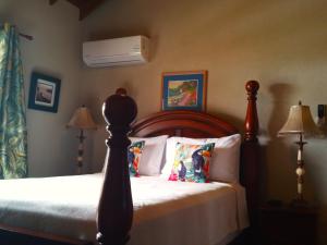 a bedroom with a bed and a fan on the wall at Coconut Walk Beach Apartment in Christ Church