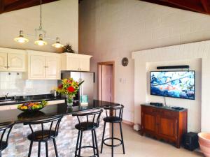 a kitchen with a counter with chairs and a tv at Coconut Walk Beach Apartment in Christ Church +31 photos