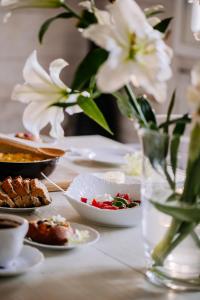 uma mesa com pratos de comida e um vaso de flores em Dwór Cieszkowskich 