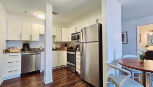 uma cozinha com armários brancos e um frigorífico de aço inoxidável em The Lofts on Clematis 407 Downtown West Palm Beach em West Palm Beach