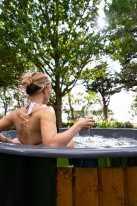uma mulher segurando um copo de vinho em uma banheira de hidromassagem em Gileston Manor Luxury B&B em Barry