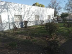 a white building with bushes in front of a yard at La Casona de la tía in La Consulta