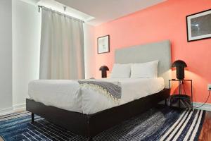 1 dormitorio con 1 cama grande y pared de color naranja en The Lofts on Clematis 504 Downtown West Palm Beach, en West Palm Beach