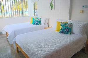 2 Betten in einem Zimmer mit weißer Bettwäsche und Kissen in der Unterkunft Magico Apartamento Frente al Mar 3 Habitaciones C11A in Coveñas