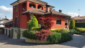 una gran casa roja con arbustos delante en GIRASOLE Wellness e Relax, en Fossano