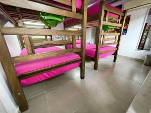 a room with two bunk beds with pink cushions at Hostal Paraiso Minca in Minca