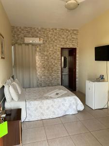 a hotel room with a bed and a television at Pousada Canaã in São Francisco de Itabapoana