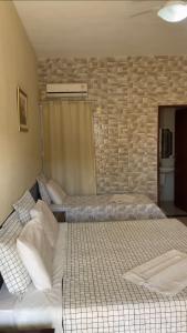 two beds in a room with a stone wall at Pousada Canaã in São Francisco de Itabapoana