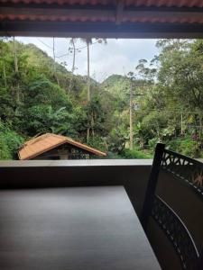 a balcony with a bench and a view of a forest at Descanso imerso à natureza! in Nova Friburgo
