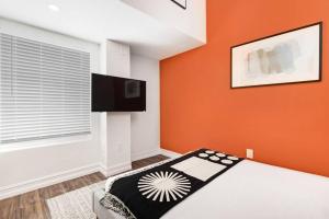1 dormitorio con una pared de color naranja, 1 cama y TV de pantalla plana en The Lofts on Clematis 603 Downtown West Palm Beach en West Palm Beach