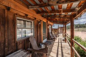 a porch of a wooden cabin with benches and a window at New! Charming cozy Cabin Colorado National Forest in Lake George