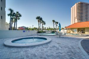 a hot tub in a patio with palm trees and a building at Heated Pool Access Clearwater Beachfront Condo! in Clearwater Beach
