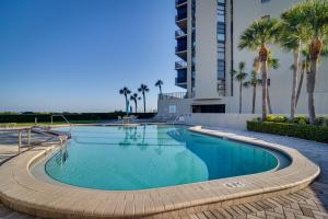 a swimming pool with palm trees and a building at Heated Pool Access Clearwater Beachfront Condo! in Clearwater Beach