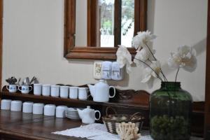 un jarrón con flores sobre una mesa con tazas y un espejo en El Colonial en Colón