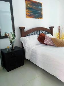 a bedroom with a bed with white sheets and a night stand at Casa Carolina in Santa Marta