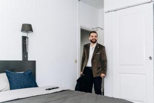 a man standing in a room next to a bed at Atomihotel: Contemporary Comfort Steps from the Atomium! in Brussels