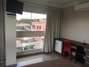 a bedroom with a desk and a large window at Hotel Mascarello in Planalto