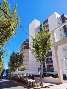un edificio bianco con alberi di fronte di Vistas al mar. Junto a la playa. Garaje y piscina. a Calpe