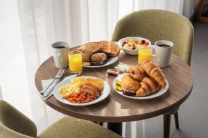 a table topped with plates of breakfast foods and orange juice at Staybridge Suites Brighton by IHG in Brighton & Hove