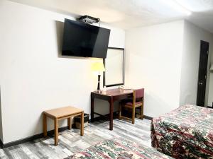 Habitación de hotel con escritorio y TV en la pared en Azure Sky Motel, en Fort Scott