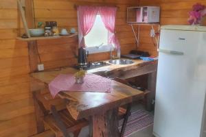 a small kitchen with a table and a refrigerator at Cabana no alto do morro in Nova Petrópolis