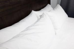 uma cama com lençóis brancos e almofadas em Lux Ramey Cir D 2 king bed w/Wi-Fi near airport. em Aguadilla