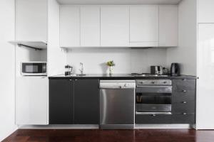 a kitchen with white cabinets and stainless steel appliances at Urban Oasis in the Heart of Richmond Cultural Hub in Melbourne