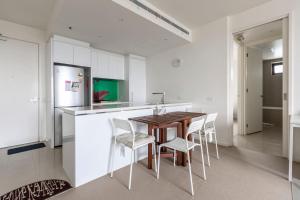 uma cozinha com uma mesa e cadeiras e um frigorífico em Light, Elevated Living near Queen Victoria Market em Melbourne