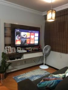 a living room with a flat screen tv and a fan at Quarto para Casal Blumenau in Blumenau