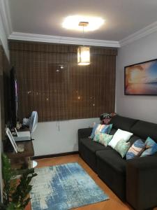 a living room with a black couch and a window at Quarto para Casal Blumenau in Blumenau