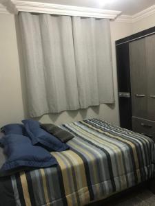 a bedroom with a bed with blue pillows and a window at Quarto para Casal Blumenau in Blumenau