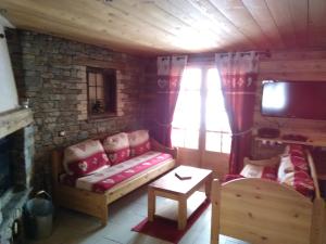 ein Wohnzimmer mit einem Sofa und einem TV in der Unterkunft Chalet la Tuilière***** in Bonneval-sur-Arc