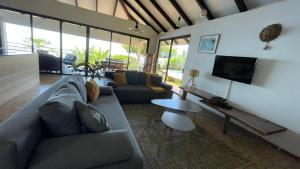 a living room with a couch and a tv at Villa Te Miti in Punaauia