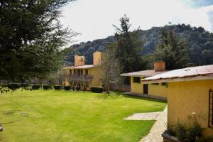 a house with a green yard with a mountain in the background at Finca Marix in Villa del Carbón