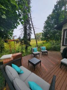 eine Terrasse mit einem Sofa und Stühlen auf einer Holzterrasse in der Unterkunft Cozy Country Home 