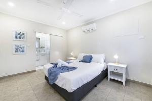 a white bedroom with a bed and a night stand at Discover a Scandi Style Pool Retreat in Nightcliff in Darwin +21 photos