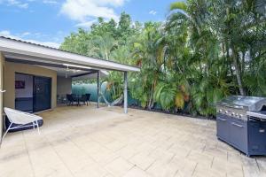 um pátio exterior com comodidades para churrascos e palmeiras em Ah Mat Bungalow - Tropical Darwin Stay with Pool em Parap