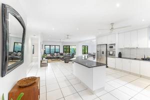 een open keuken en een woonkamer met witte kasten bij Ah Mat Bungalow - Tropical Darwin Stay with Pool in Parap