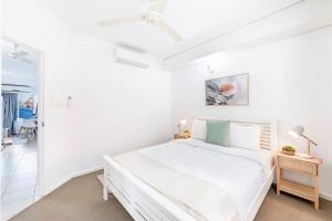 a white bedroom with a large bed and a hallway at Cullen Bay Calm - Tropical Poolside Living in Larrakeyah