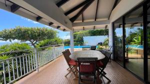 patio con mesa y sillas en el balcón en Villa Te Miti, en Punaauia