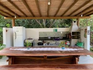 a large wooden table with a kitchen in the background at Bons Ventos Bangalôs e Camping in Barra Grande