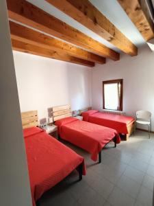 una camera con tre letti con lenzuola rosse di Il Nido - Villetta in posizione strategica a Treviso