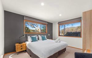 a bedroom with a large bed and two windows at Lily Chalet in Crackenback